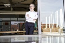 Businessman standing at French door thinking — Stock Photo