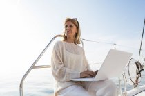Femme assise sur catamaran, à l'aide d'un ordinateur portable — Photo de stock
