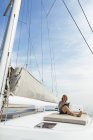 Woman sitting on deck of a catamaran, reading a book — Stock Photo