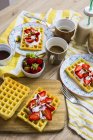Gofres decorados con fresas, yogur griego y almendras en la mesa de desayuno - foto de stock