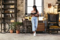 Young woman standing in front of desk in a loft using notebook — Stock Photo