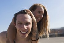 Porträt eines glücklichen jungen Mannes, der seiner Freundin Huckepack fährt — Stockfoto