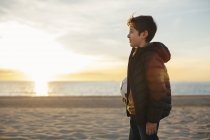 Junge hält Fußballball am Strand bei Sonnenuntergang — Stockfoto