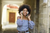 Portrait of smiling young woman listening music with headphones — Stock Photo