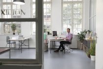 Man working at desk in a loft office — Stock Photo