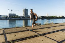 Young athlete jogging in the city at the river — Stock Photo