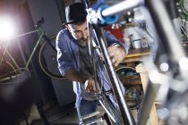 Homme travaillant sur vélo en atelier — Photo de stock