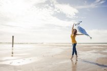 Donna felice divertirsi in spiaggia, ballare e asciugamano ondeggiante — Foto stock