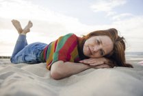Mulher ruiva deitada na areia na praia — Fotografia de Stock
