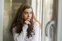 Teenage girl looking out of window, daydreaming — Stock Photo