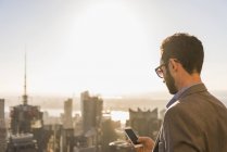 Соединенные Штаты Америки, New York City, businessman with cell phone on Rockefeller Center observdeck — стоковое фото