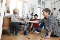 Happy family sitting on ground, playinhg with their little daughter — Stock Photo