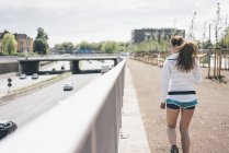 Спортивная молодая женщина, идущая вдоль автострады — стоковое фото