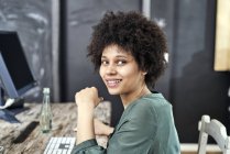 Portrait of smiling young woman at wooden table in office — Stock Photo