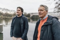 Senior man and young man standing at the riverside — Stock Photo