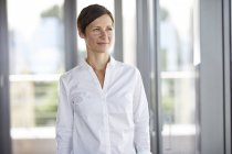 Smiling businesswoman in office looking sideways — Stock Photo
