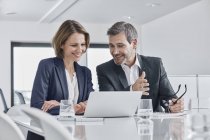 Businessman and businesswoman having a meeting in office with laptop — Stock Photo