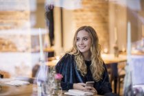 Retrato de jovem sorridente esperando no restaurante — Fotografia de Stock