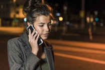 Jeune femme au téléphone la nuit — Photo de stock