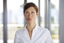 Porträt einer Geschäftsfrau im Büro, die schmollend nach oben blickt — Stockfoto