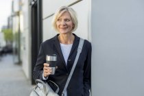 Sonriente mujer de negocios senior con café para llevar al aire libre - foto de stock