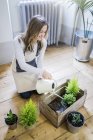 Усміхаючись жінка поливу рослин в домашніх умовах — стокове фото