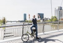 Heureux homme mature avec vélo écouter de la musique sur le pont dans la ville — Photo de stock