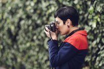 Fashionable young woman taking photo with camera — Stock Photo