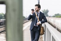 Lächelnder Geschäftsmann mit Handy am Bahnsteig — Stockfoto