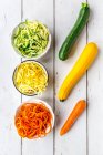 Zoodles, calabacín verde y amarillo, zanahoria sobre madera blanca - foto de stock