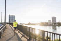 Молодий спортсмен біжить по мосту в місті — стокове фото
