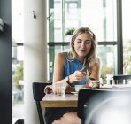 Jeune femme au café, boire du café et manger des bonbons — Photo de stock
