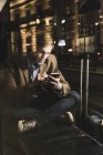 Businessman using cell phone at tram station at night — Stock Photo