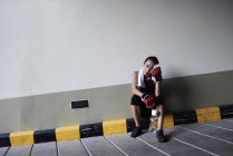 Boxeadora sentada en un garaje sosteniendo una toalla - foto de stock
