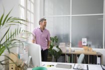 Man standing at the window in a loft office — Stock Photo