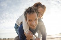 Casal na praia, homem carregando mulher piggyback — Fotografia de Stock