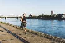 Jovem atleta correndo na cidade no rio — Fotografia de Stock