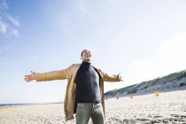 Homme heureux debout sur la plage avec les bras tendus — Photo de stock