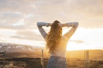 Iceland, young woman with hands in hair at sunset — Stock Photo