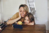 Mother and little daughter using smartphone at new home — Stock Photo