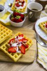 Вафельний прикрашений полуницею, грецький йогурт і мигдаль на сніданок стіл — стокове фото