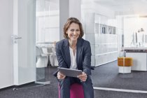 Retrato de una mujer de negocios sonriente usando tableta en la oficina - foto de stock