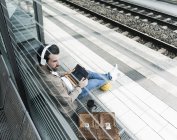 Young man with basketball using tablet at the station platform — Stock Photo