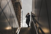 Mature businessman at staircase in the city on cell phone — Stock Photo