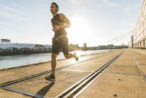 Jeune athlète jogging dans la ville à la rivière — Photo de stock