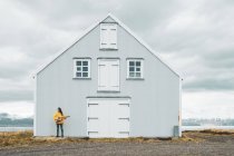 Islândia, mulher tocando guitarra na casa solitária — Fotografia de Stock