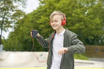 Junge mit Kopfhörer tanzt, während er Musik auf dem Smartphone hört — Stockfoto