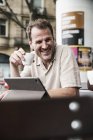 Hombre sonriente con tableta y café en un café al aire libre - foto de stock