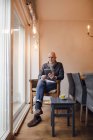 Homme âgé assis à la maison, lecture sur tablette numérique — Photo de stock