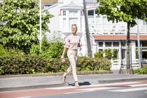 Donna sorridente che attraversa una strada — Foto stock